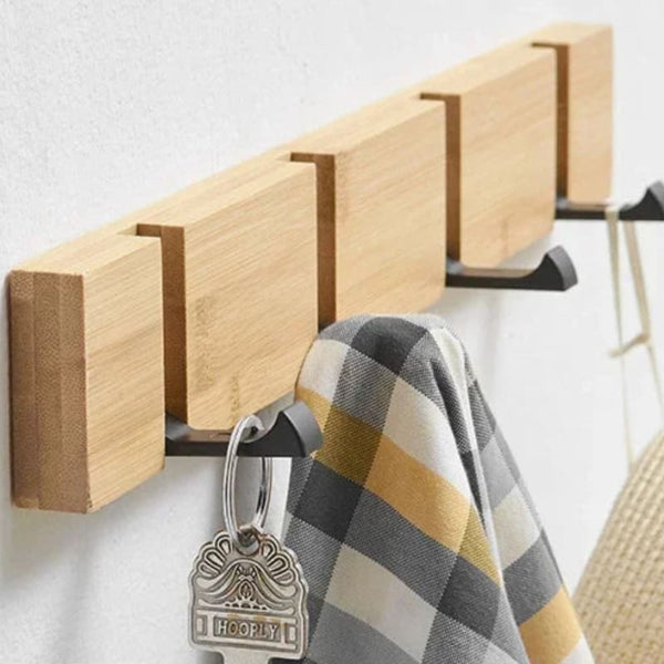Bamboo wall rack showing 90-degree flip hooks holding clothes and bags for practical hanging.