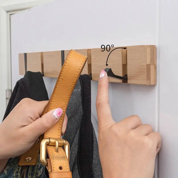 Bamboo wall rack showing 90-degree flip hooks holding clothes and bags for practical hanging.