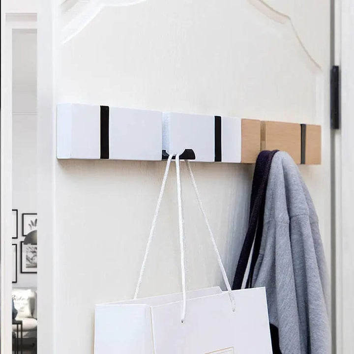 White and bamboo wall-mounted hanger with multiple hooks used to store a bag and jacket.