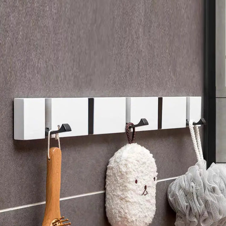 White wall-mounted hook rack in bathroom setting holding brushes and bath accessories.