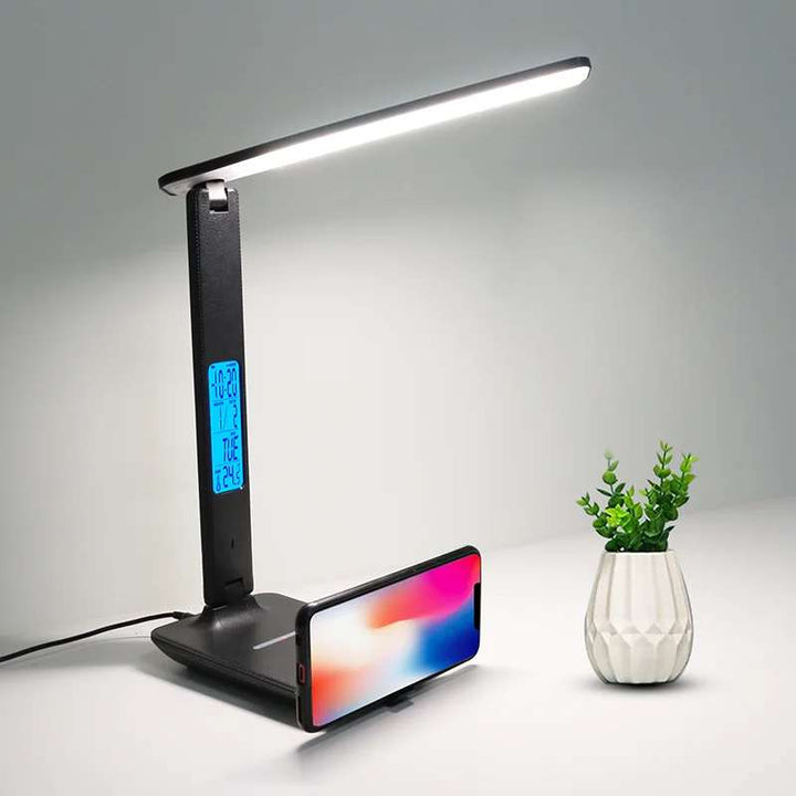 Modern LED desk lamp with wireless charging base and blue LCD clock display on a clean workspace