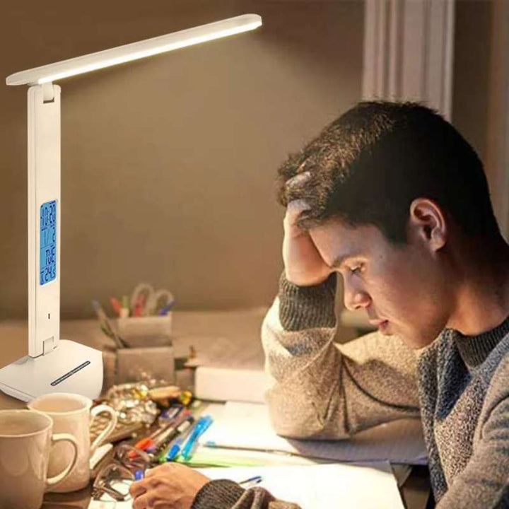 Warm LED desk lamp lighting a study desk while a student reads under soft focused illumination