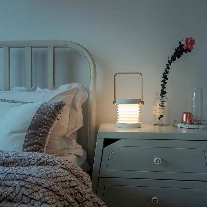 LYKT foldable LED bedside lamp with wooden handle, softly illuminating a Scandinavian bedroom nightstand.