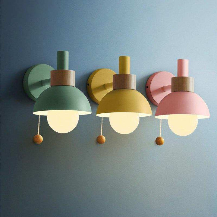 Trio of pastel wall sconces in green, yellow and pink with globe bulbs for modern interior styling.