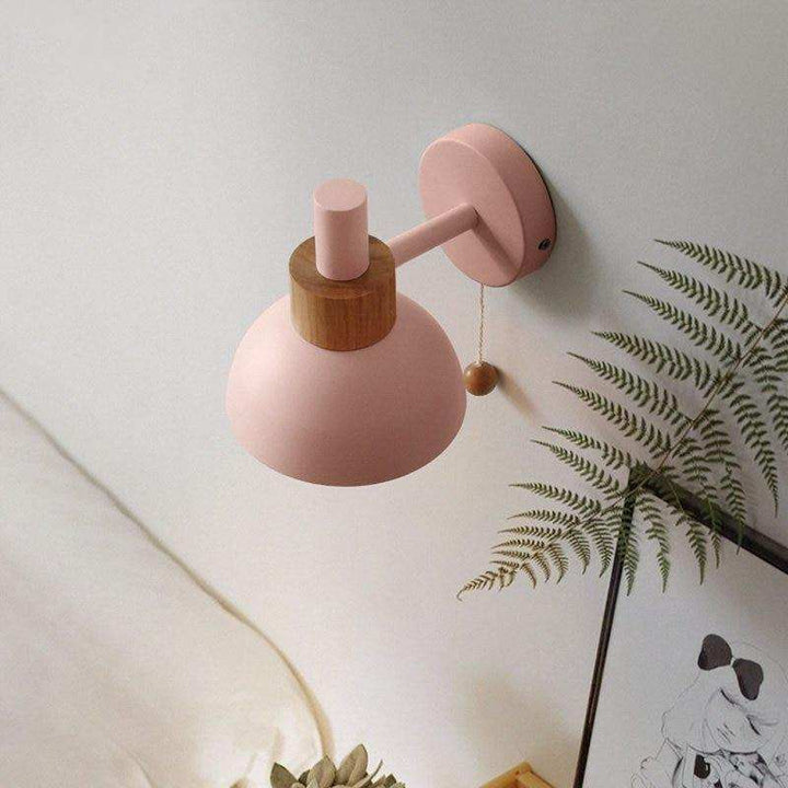 Pink wall sconce with wood detail above a framed print, perfect for cosy Scandinavian bedrooms.