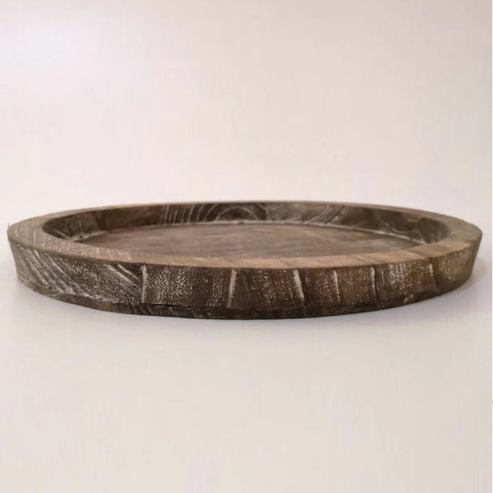 Side view of round brown wooden tray showing carved edge and smooth natural texture