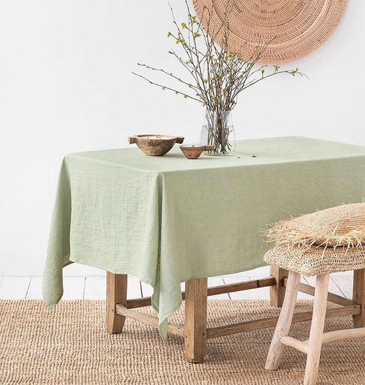 sage-green Line tablecloth on a wooden table with decorative items in a room.