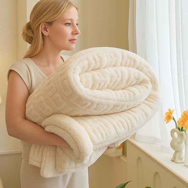 Woman holding a large beige blanket in a bright room with flowers on a windowsill.