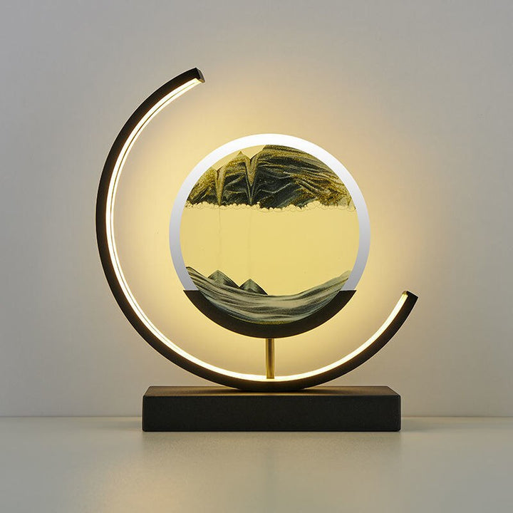 Crescent-frame quicksand lamp showcasing dark green sand landscape in round PMMA disc.