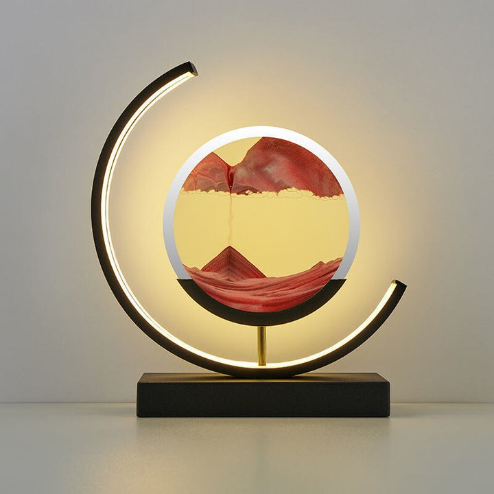 Black crescent-frame quicksand lamp with red flowing sand art in a round PMMA display.