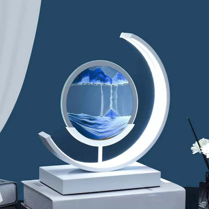 White crescent-frame quicksand lamp with blue sand landscape in clear round PMMA disc.