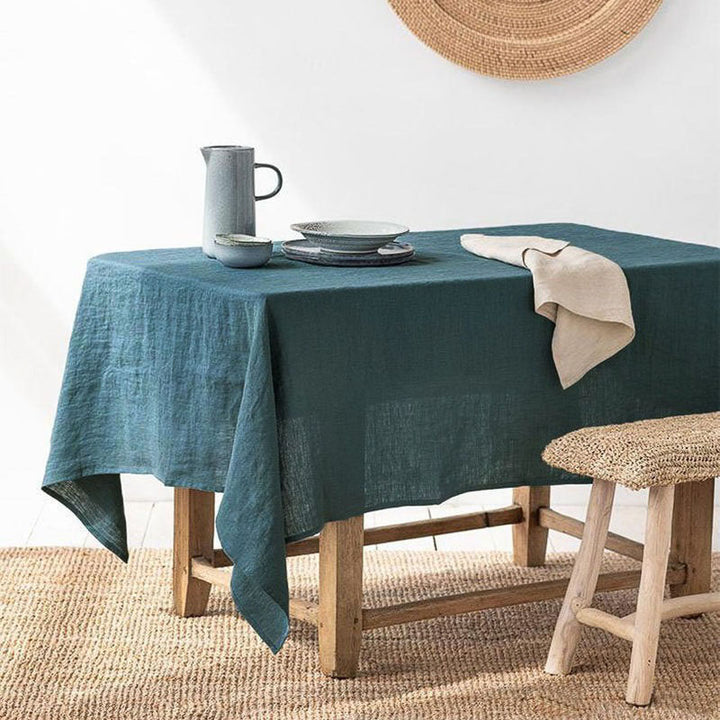 Teal blue linen tablecloth on a wooden table with a neutral color scheme