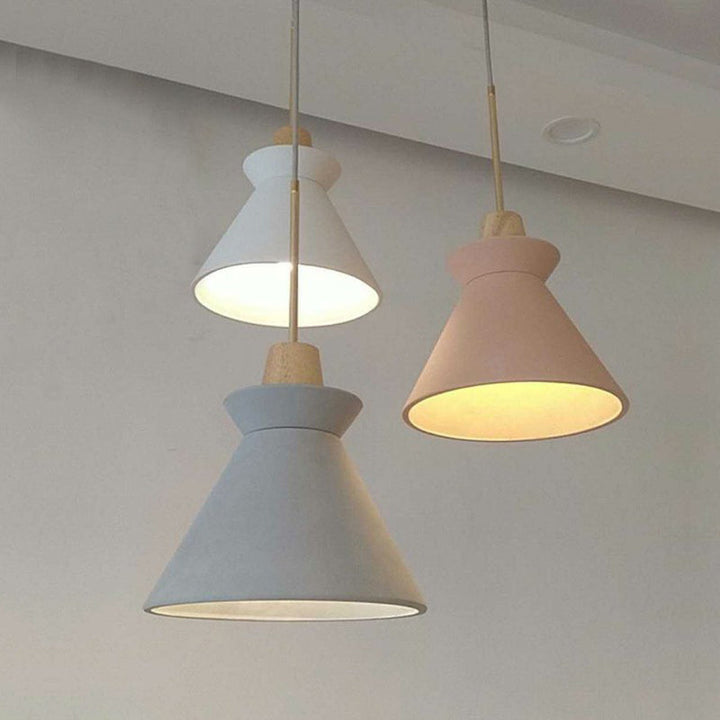 Trio of Scandinavian pendant lights in white, grey, and pink, suspended from ceiling in bright living space.
