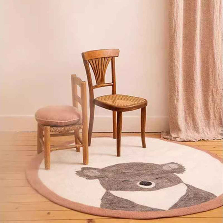 Beige koala rug beneath wooden chairs, soft faux cashmere nursery carpet for calm Scandinavian interiors.