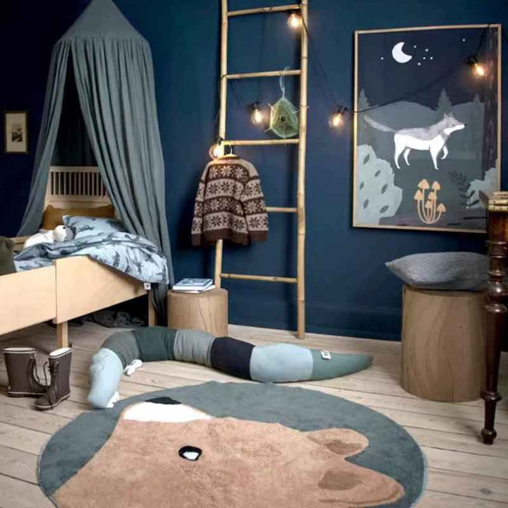 Nordic kids’ bedroom with grey canopy and brown bear rug, soft faux cashmere play mat on wooden floor.