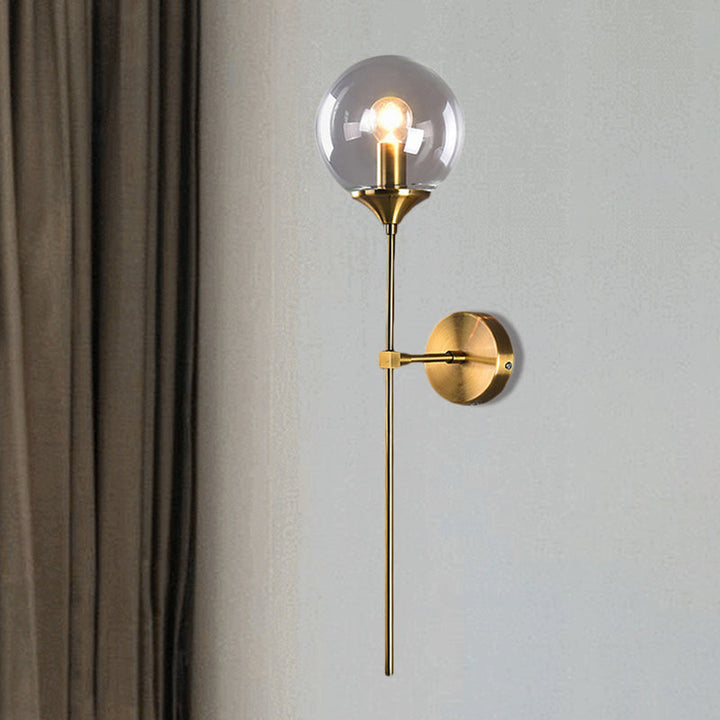 Clear glass and brass wall sconce illuminating a minimalist modern wall with elegant soft light.