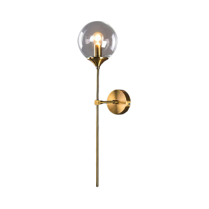 Product shot of brass wall sconce with glass globe shade against a white background.