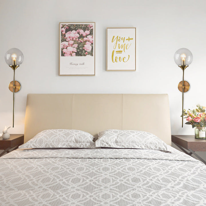 Matching pair of glass and brass wall lights framing a neutral bedroom, adding balanced Scandinavian warmth.