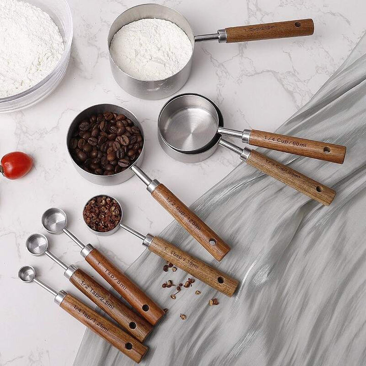 Nordic stainless steel measuring cups and spoons with wooden handles filled with flour and coffee