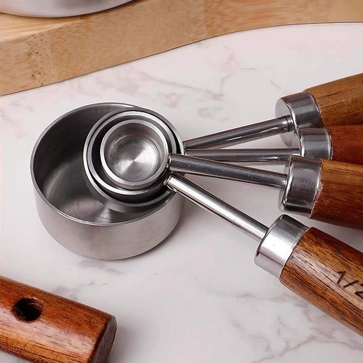 Nesting stainless steel measuring spoons with smooth wooden handles in modern kitchen setting